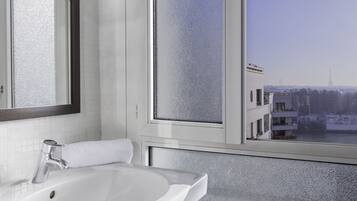 Une salle de bain avec un lavabo blanc, un miroir et une fenêtre à vitre dépolie.