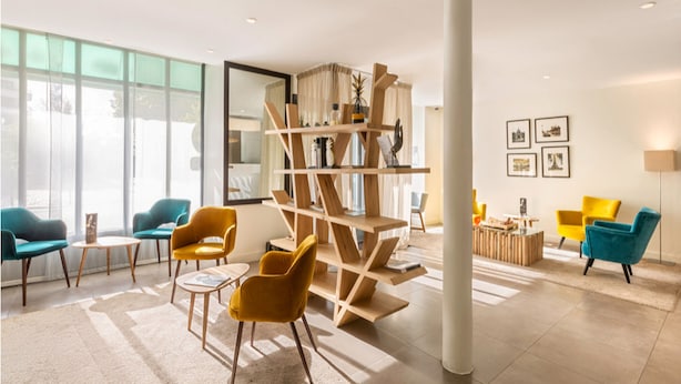 Un moderno vestíbulo de hotel con un ventanal grande, una estantería de madera y varias sillas.