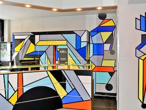 Un intérieur moderne agrémenté d’œuvres d’art géométriques murales, d’un comptoir d’accueil et d’une cloison en verre.