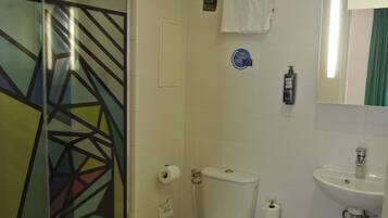 Un baño con inodoro, lavamanos y cabina de ducha de vidrio.