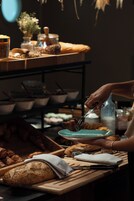 A kitchen counter with various food items and utensils, including a loaf of bread, a cutting board, and a plate with a utensil.