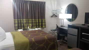 A hotel room with a bed, a desk, a computer, a television, and a minibar.