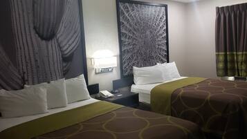 A hotel room with two beds, a nightstand, a lamp, and a patterned wall.