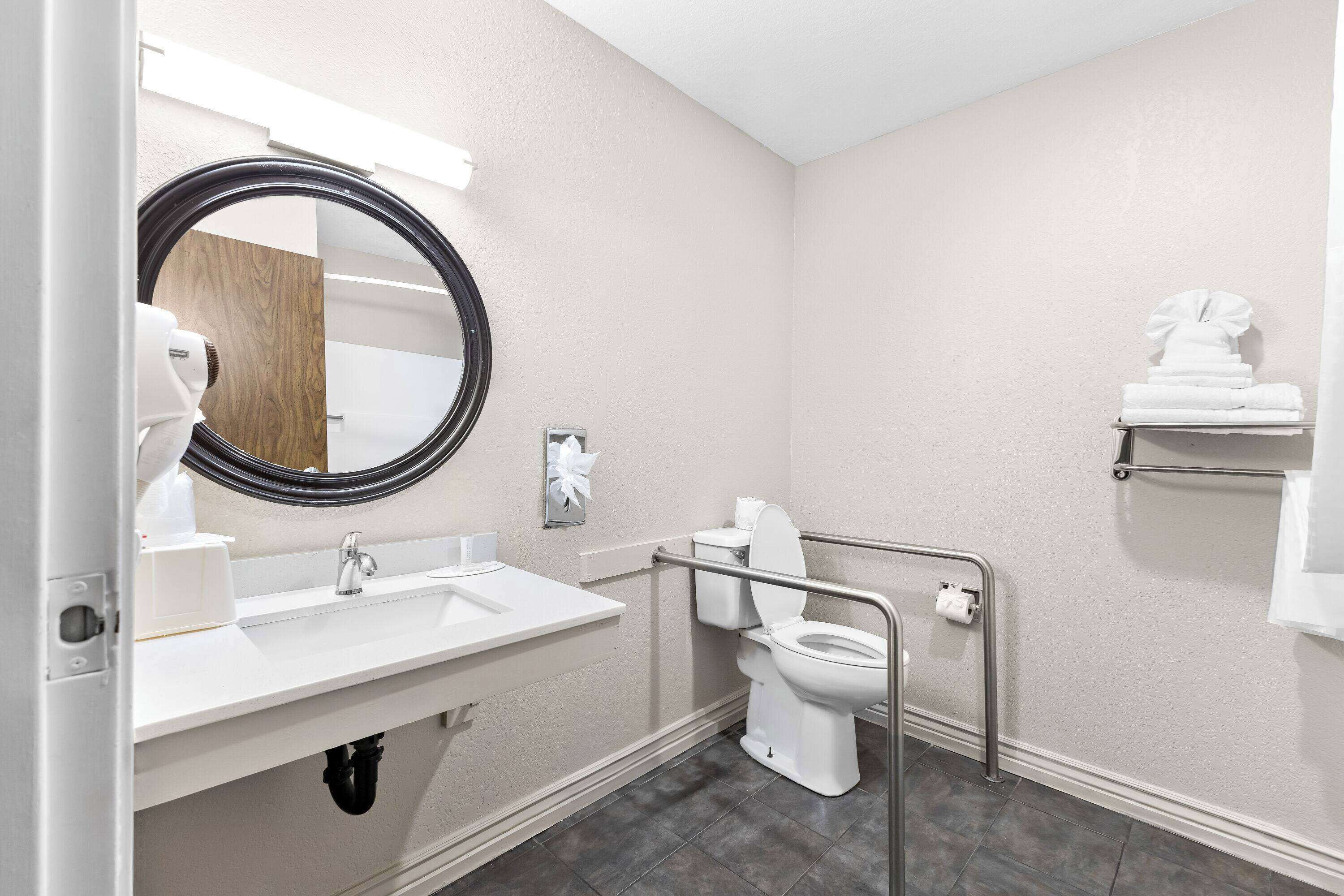 A bathroom with a white sink, mirror, toilet, and a towel rack.