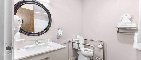 A bathroom with a white sink, mirror, toilet, and a towel rack.