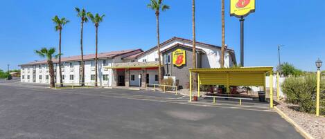 A Super 8 motel with a parking lot, palm trees, and a yellow covered area.