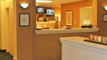 A hotel reception area with a counter, framed certificates, and a television screen.