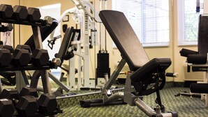 Une salle de sport équipée de matériel d’exercice, notamment des haltères, un banc et des appareils de musculation.