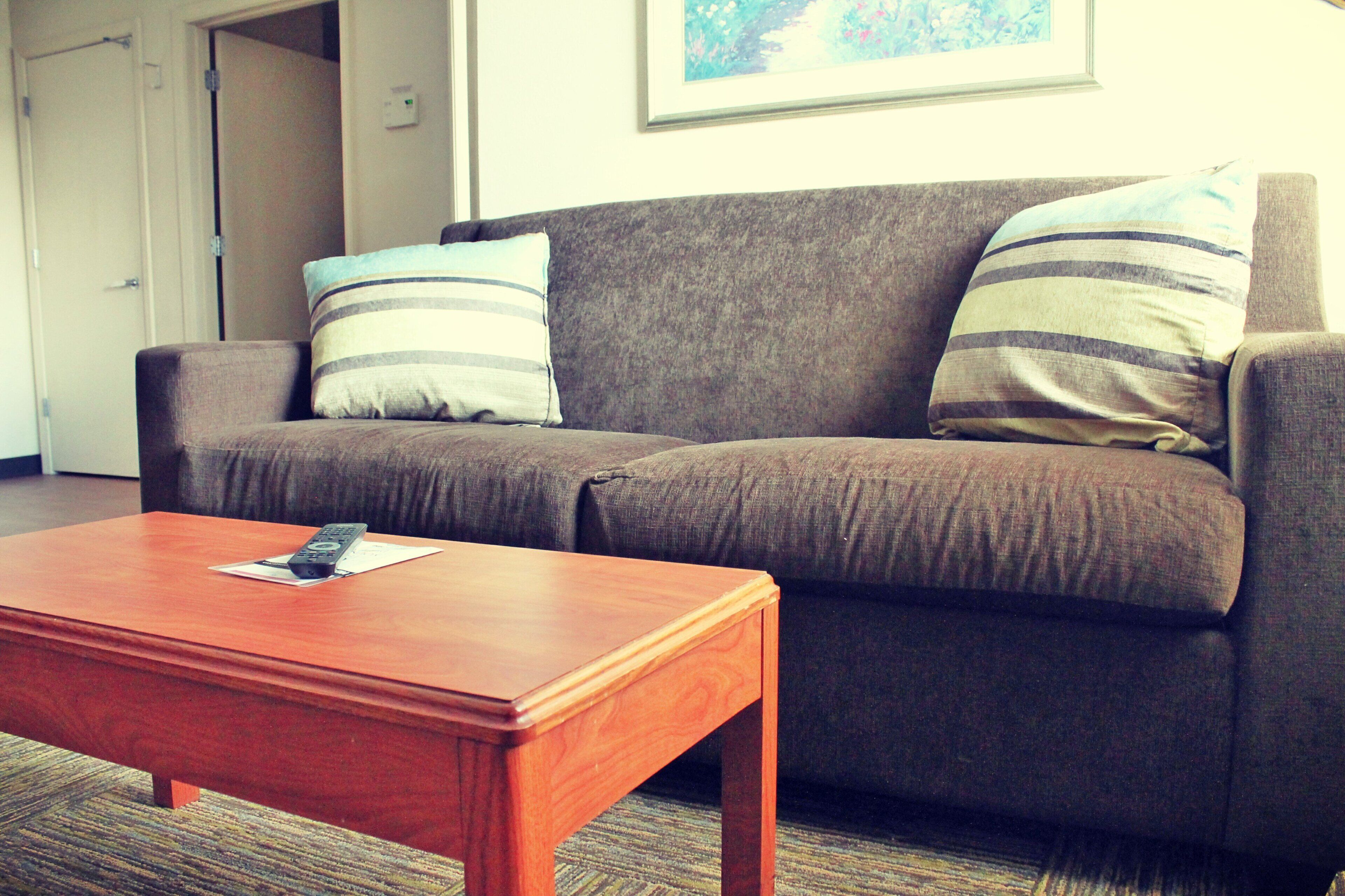 A living room with a brown sofa, two striped pillows, and a wooden coffee table.