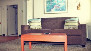 Una sala de estar con un sofá marrón, dos almohadas a rayas, una mesa de centro de madera y un cuadro en la pared.