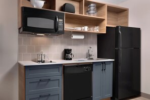 Una cucina moderna dotata di forno a microonde, macchina del caffè, lavastoviglie e frigorifero nero.