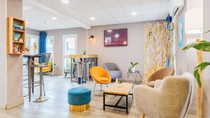 A modern hotel lobby with a bar area, seating, and a television. - KYRIAD DIRECT Tours Sud - Chambray Lès Tours (Chambray-les-Tours)
