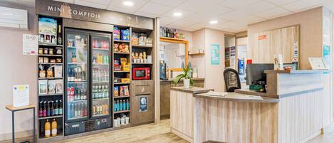 Un área de recepción con mostrador, una kitchenette pequeña y un refrigerador exhibidor.
