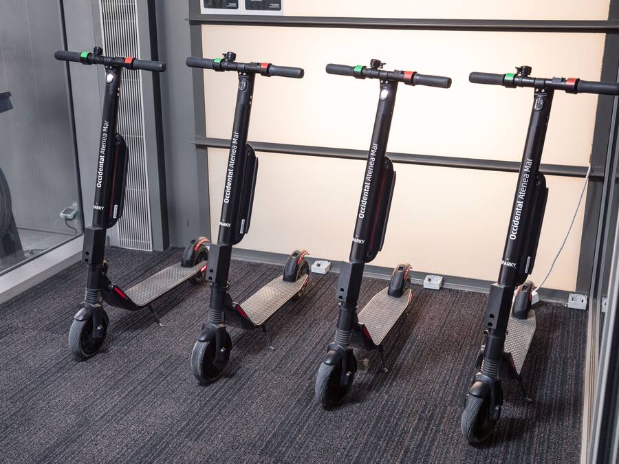 Cuatro scooters eléctricos alineados sobre un piso alfombrado.