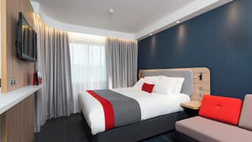 Una habitación de hotel con una cama, televisión, escritorio y sofá.