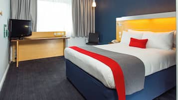 Une chambre d’hôtel avec un lit, un bureau, une télévision et une fenêtre avec des rideaux.