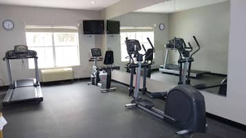Un gimnasio con cinta de correr, elíptica y bicicleta estática.