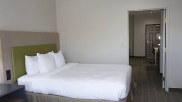Quarto de hotel com uma cama grande, cabeceira verde e porta para um banheiro.