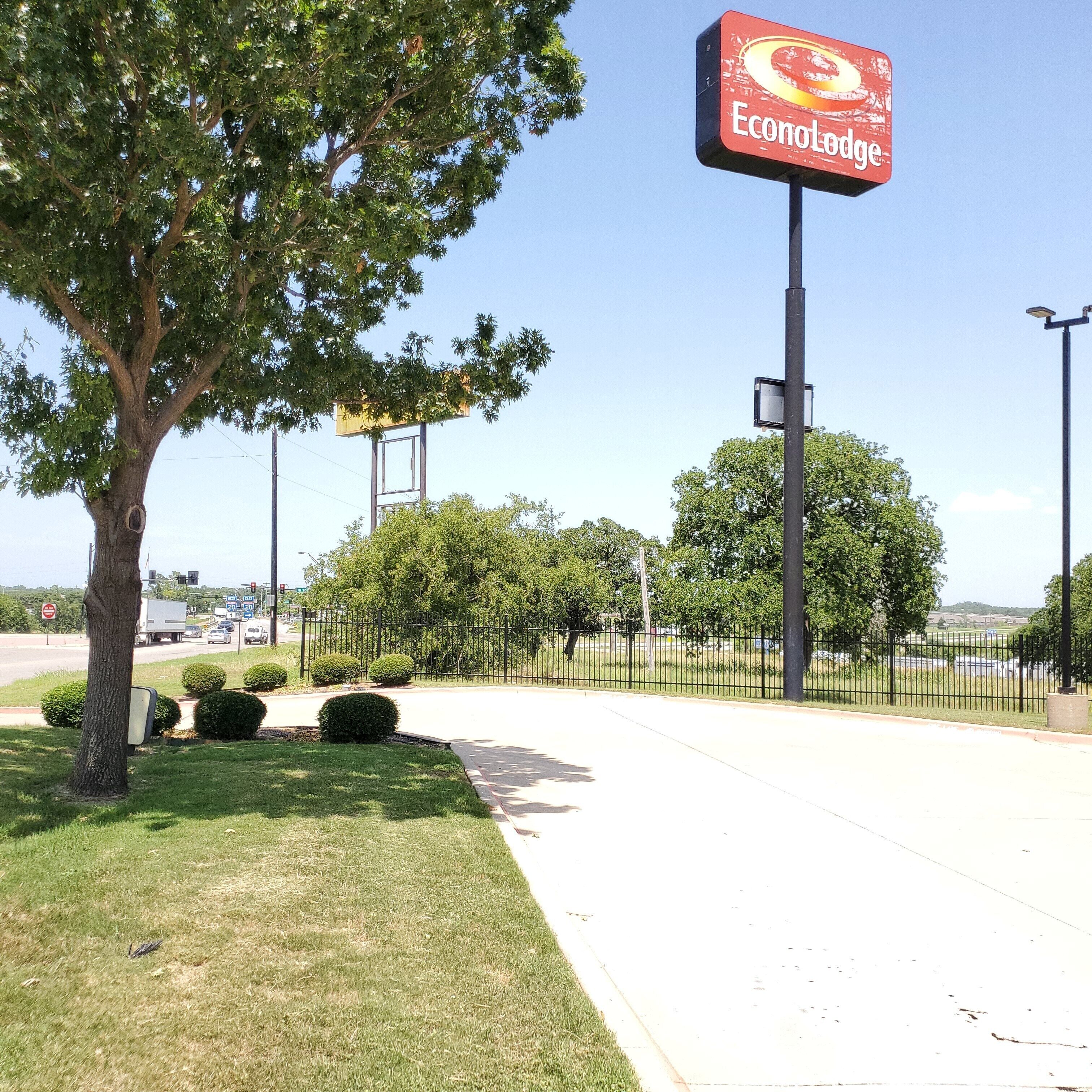 A sign for Econotodge, a fenced parking area, and a tree.