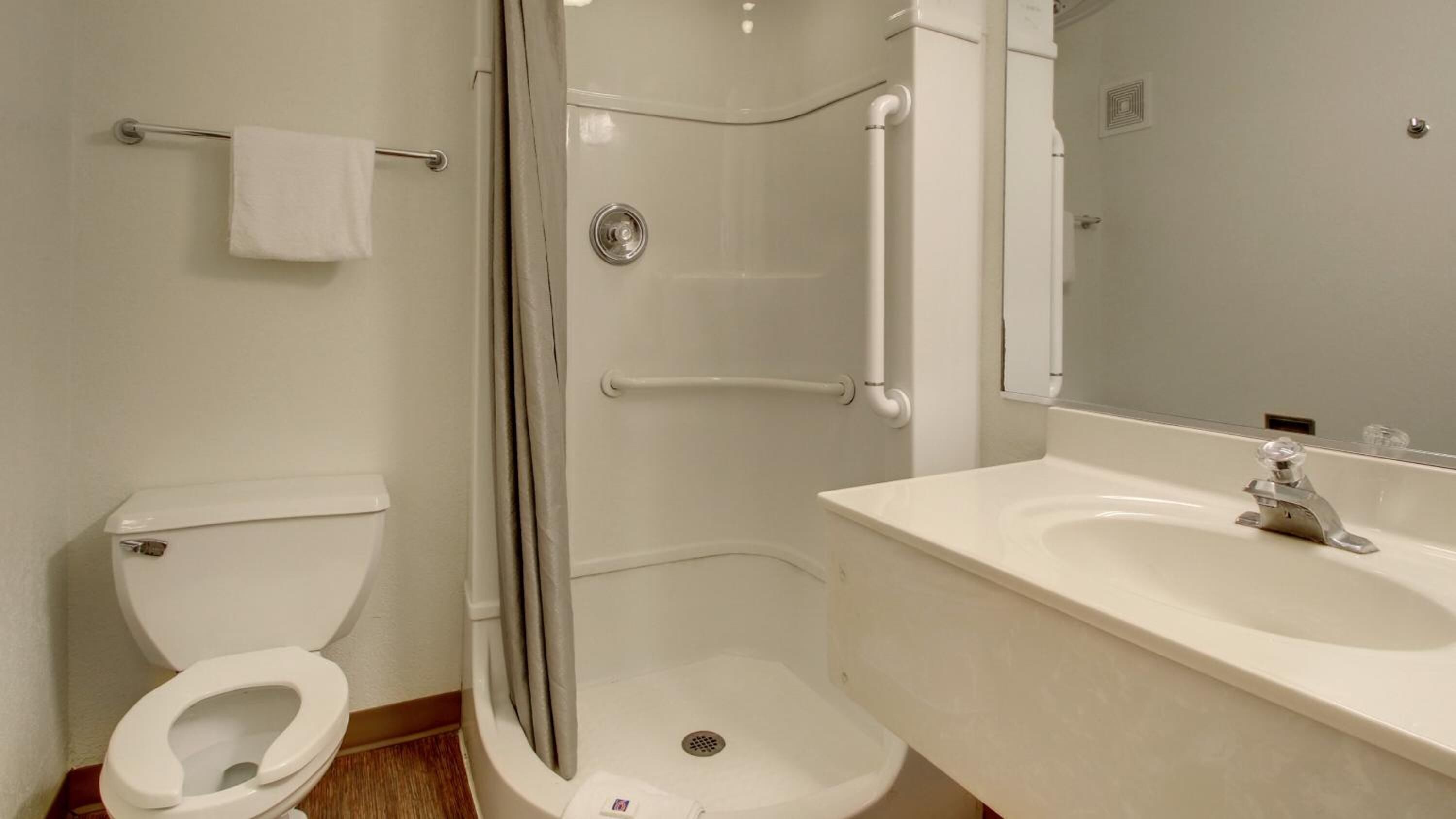 A bathroom with a toilet, a shower with a glass door, and a sink with a mirror.