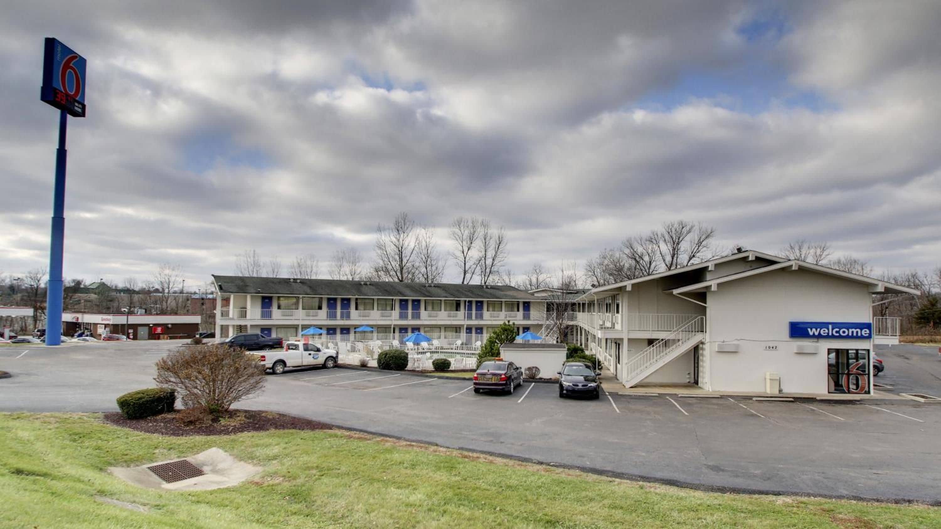A motel with a parking lot, a 'Welcome' sign, and a '6' sign indicating the number of rooms.