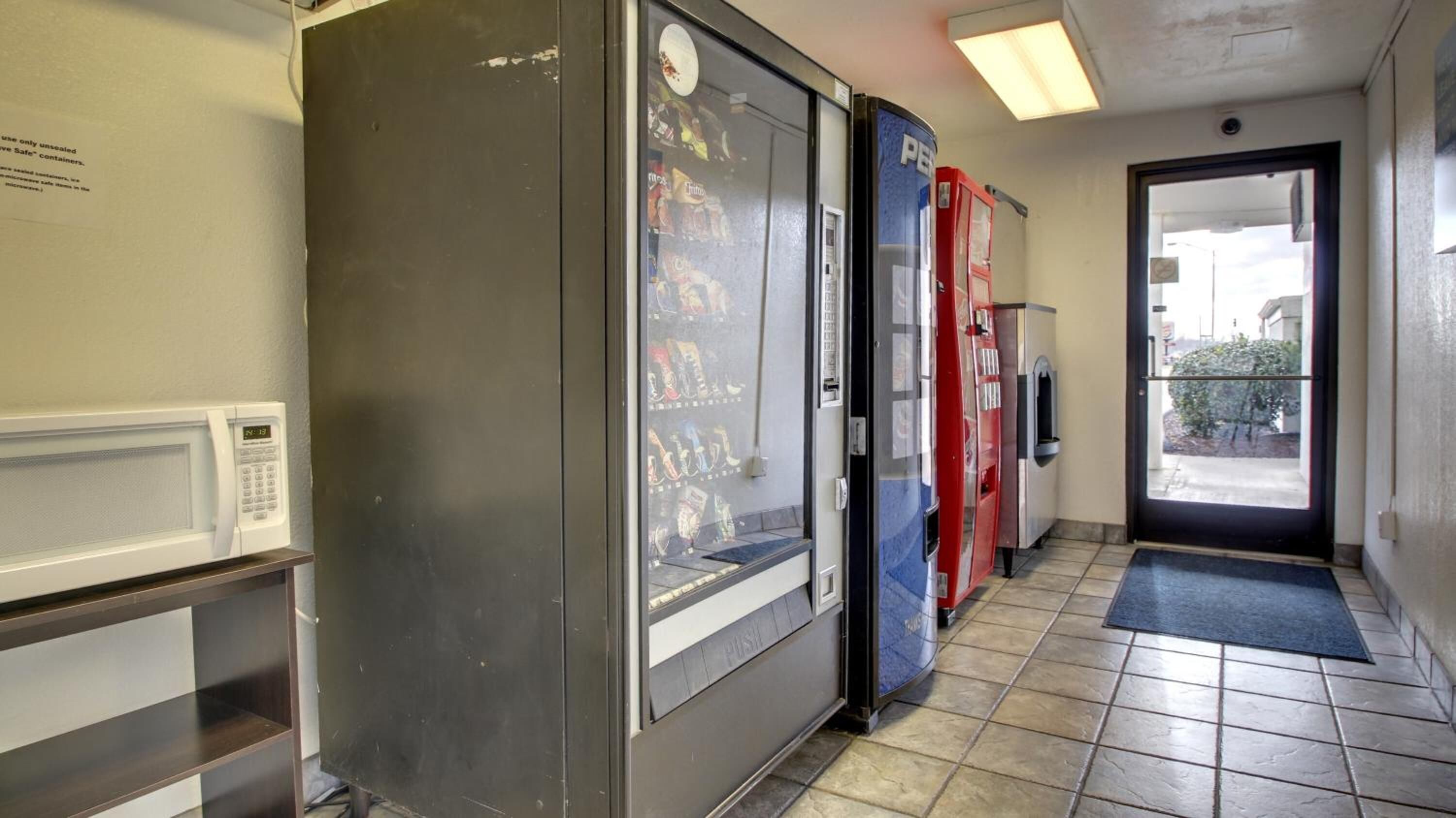 A hallway with vending machines, a microwave, and a door leading outside.
