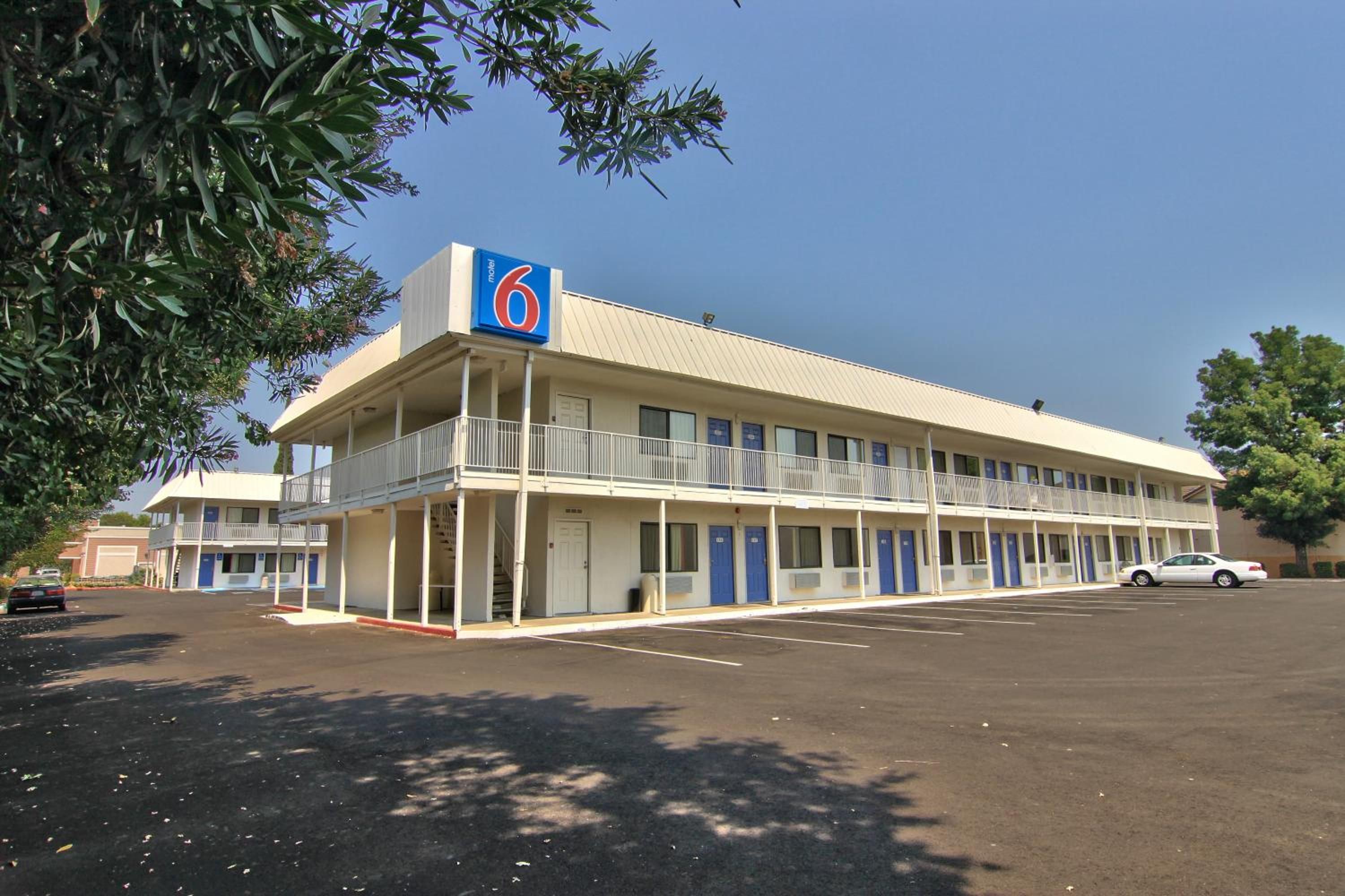 A motel with a two-story structure, a covered parking area, and a single-story building in the background.