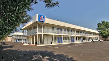A motel with a two-story structure, a covered parking area, and a single-story building in the background.