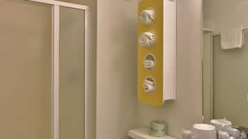 A bathroom with a toilet, sink, and shower. There are towels and toiletries on the sink counter.