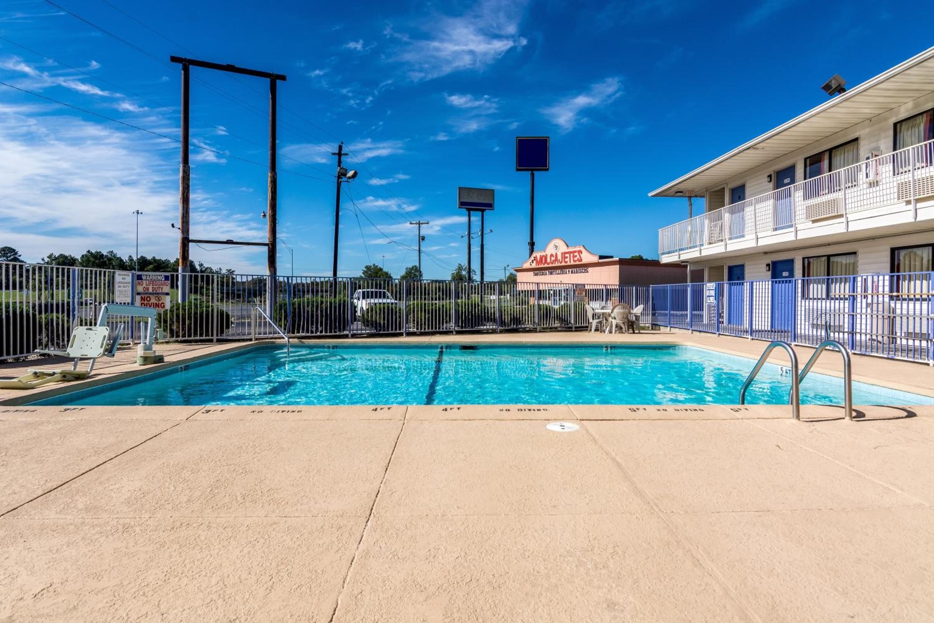 Un motel con piscina, un área cercada y un letrero que dice 'MOLI CAFE'.