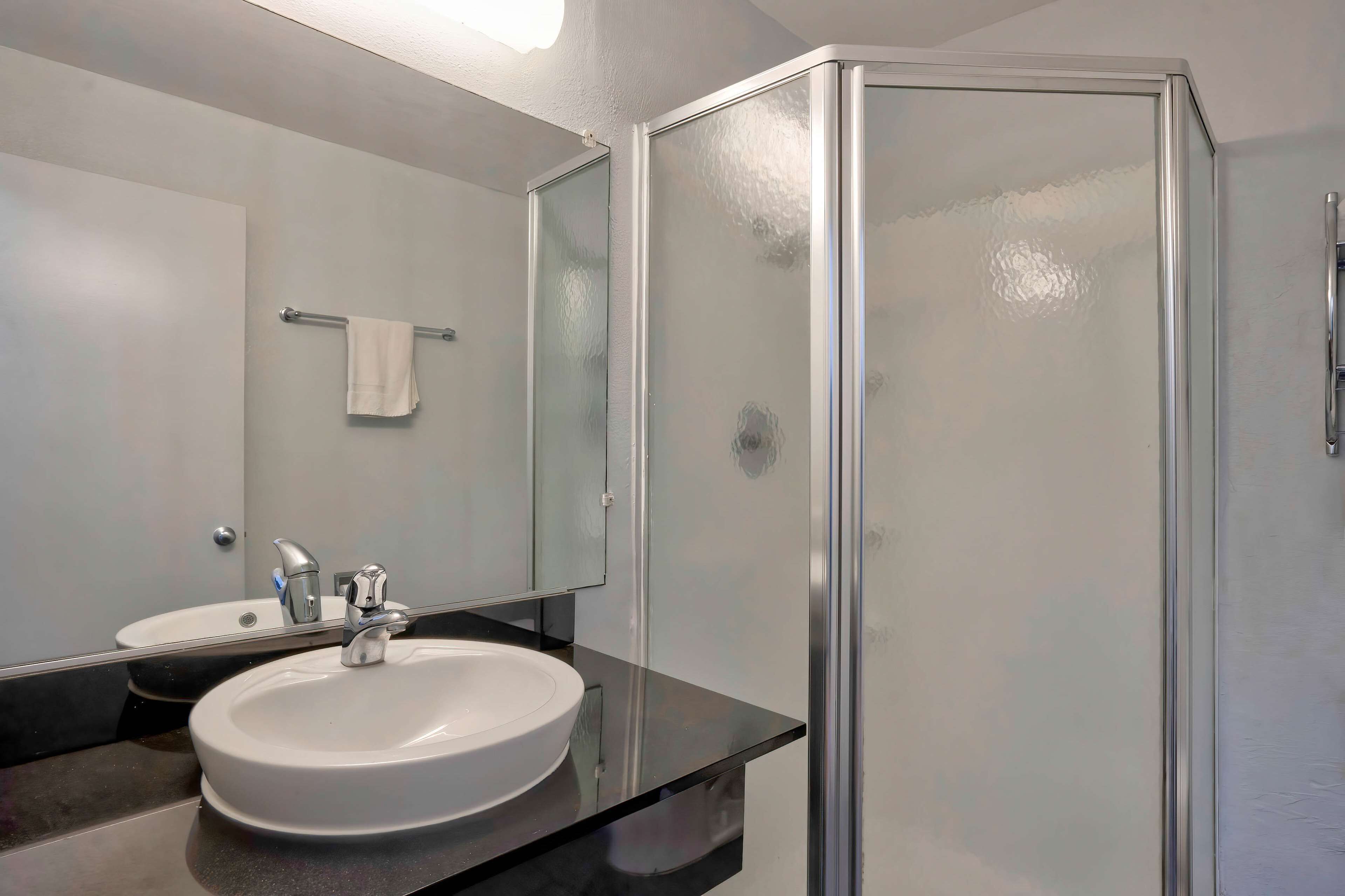 A bathroom with a white sink, a mirror, and a glass shower enclosure.