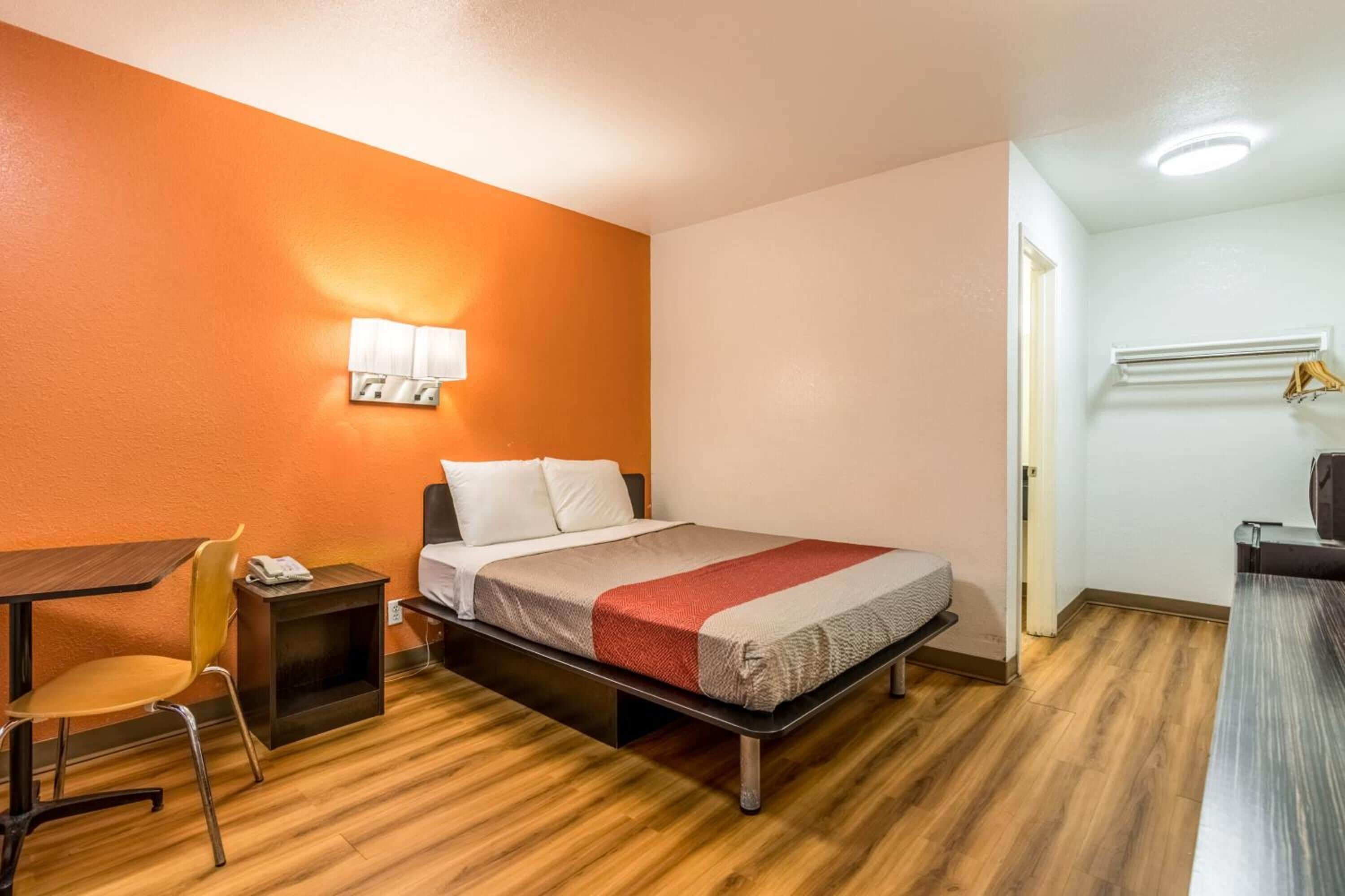 Une chambre d’hôtel de taille réduite, comprenant un lit, un bureau et une chaise.