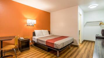 Une chambre d’hôtel de taille réduite, comprenant un lit, un bureau et une chaise.