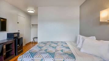 Una habitación de hotel con una cama, un escritorio con microondas y una mesita.