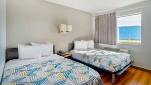 A hotel room with two beds, a nightstand, a lamp, and a window with a view of the outside. - Motel 6 Lumberton, NC (Lumberton)