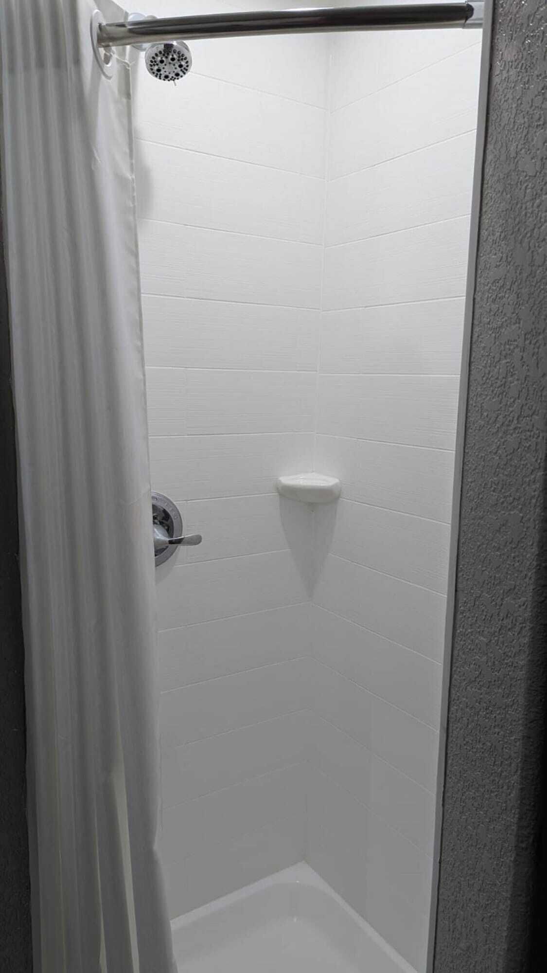 A shower with white tiled walls and a showerhead.