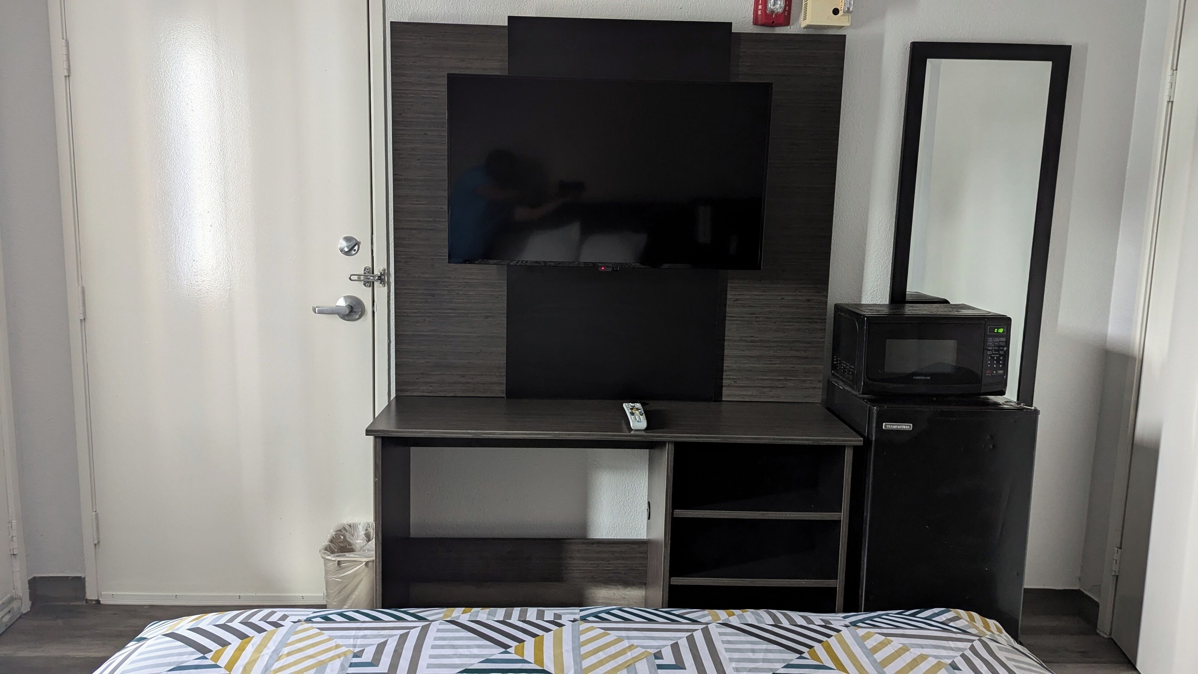 Une chambre avec un lit, une télévision, un four à micro-ondes et un miroir.