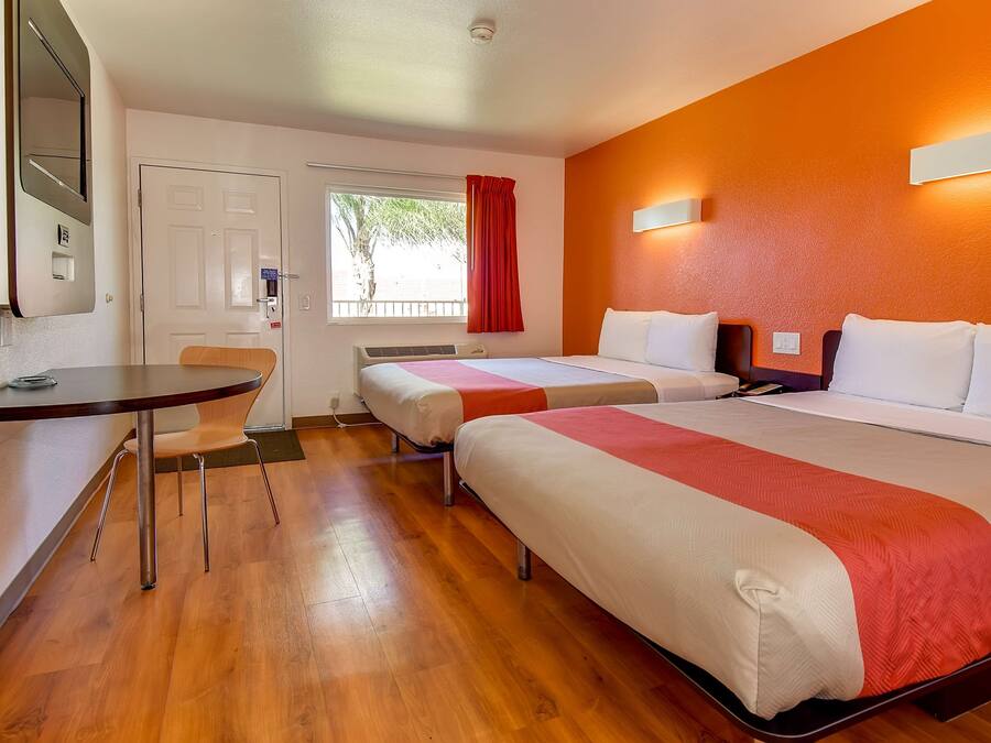 A hotel room with two beds, a desk, and a chair.