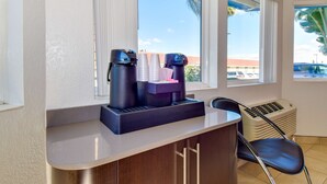 A hotel room with a coffee station, a chair, and a window with a view of the outside. - Motel 6 Riverside, CA - South (Riverside)