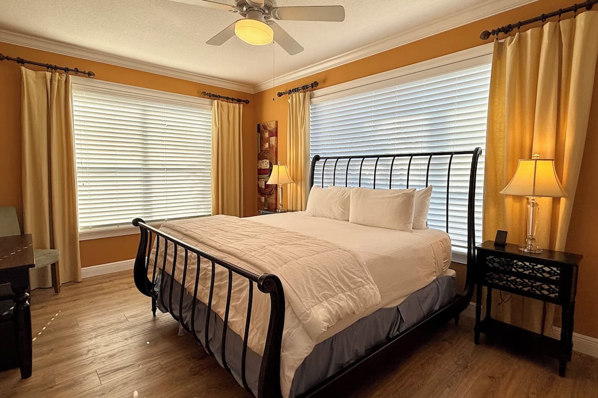 A bedroom with a bed, a ceiling fan, two bedside lamps, and a nightstand.