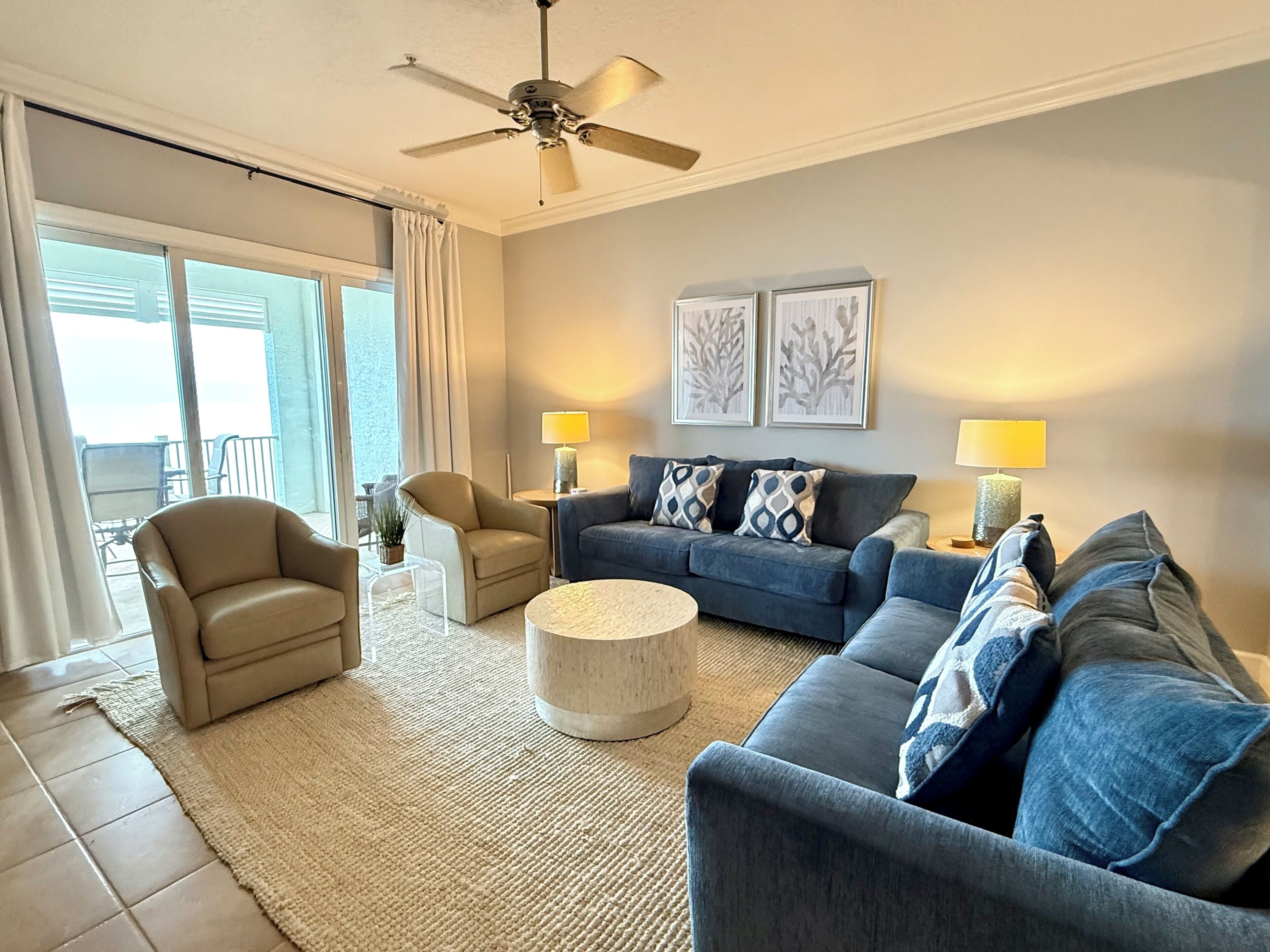 A living room with a sofa, armchairs, a coffee table, and a ceiling fan.