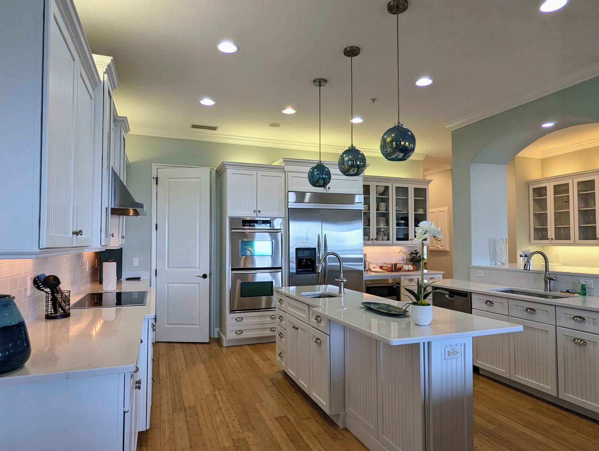 A modern kitchen with white cabinetry, stainless steel appliances, and pendant lighting.