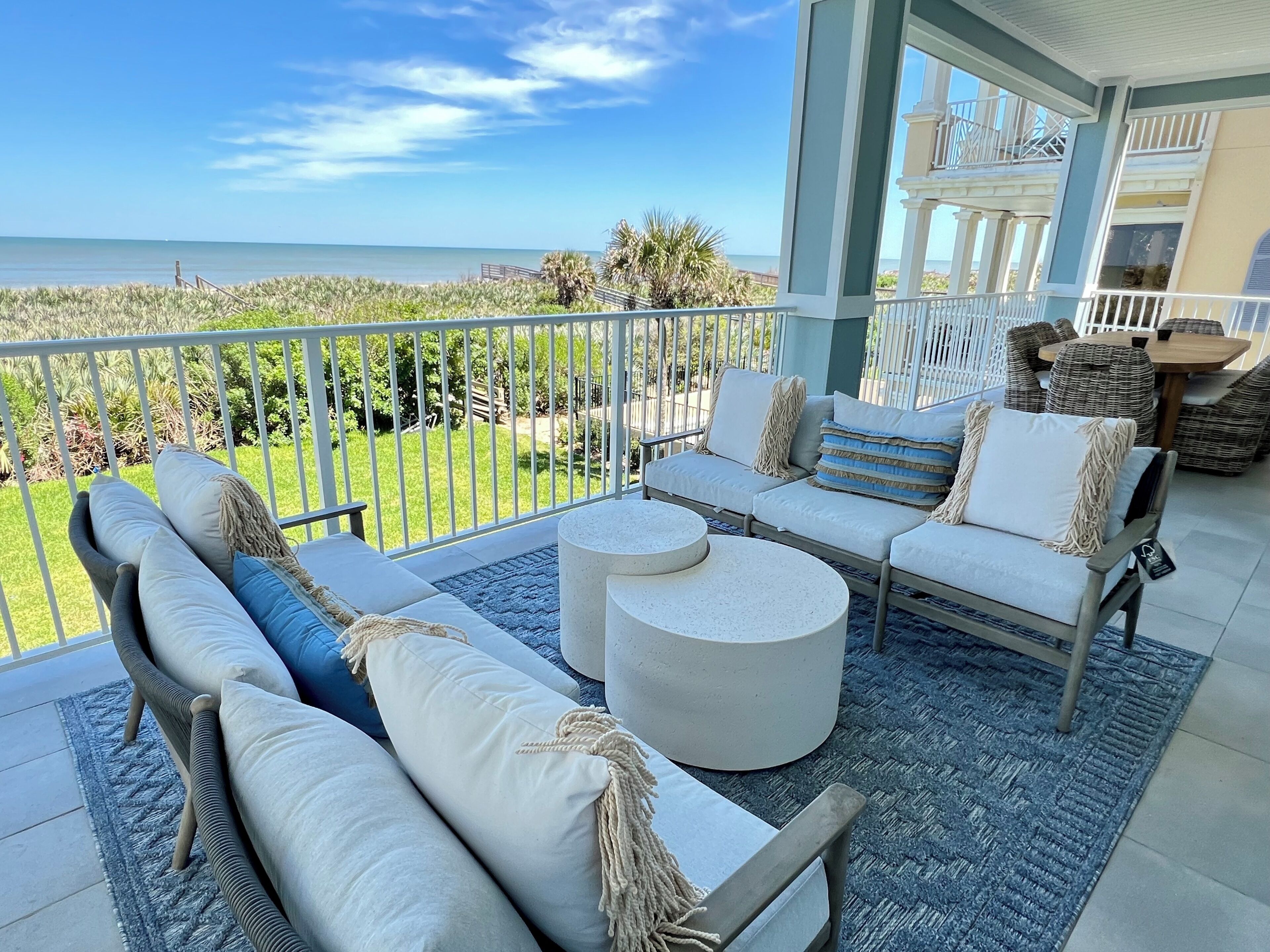 A balcony with outdoor furniture, a view of the ocean, and a building with a balcony.