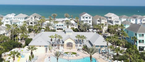 Um resort com piscina, palmeiras e vista para o oceano.