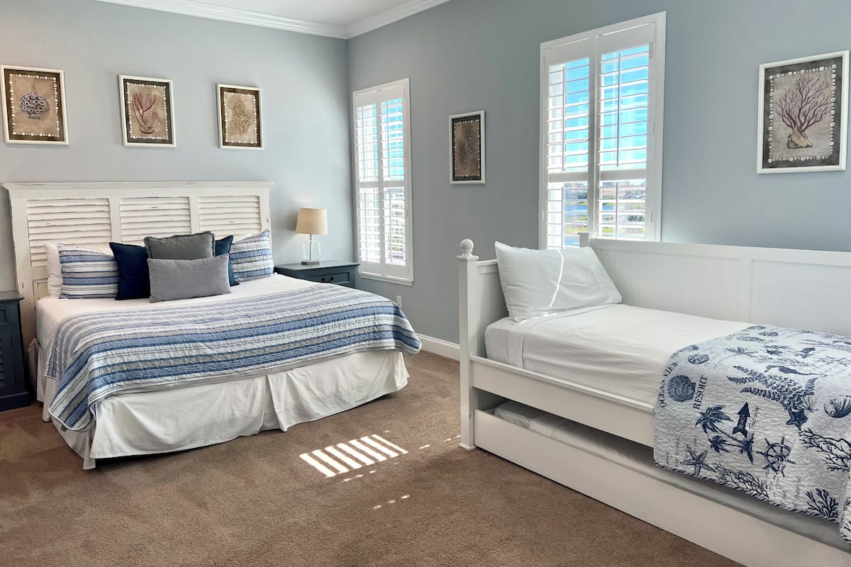 A bedroom with a bed, a nightstand, a dresser, and a window with blinds.