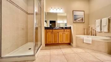 A bathroom with a glass shower enclosure, wooden cabinets, a bathtub, and a large mirror.
