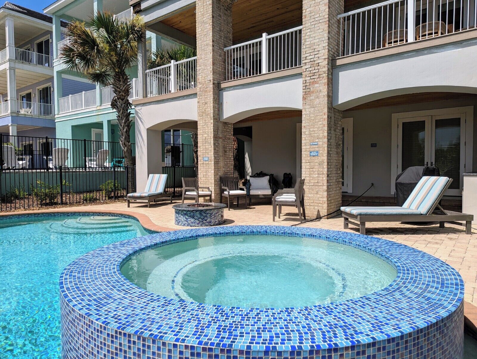 A hotel with a swimming pool, lounge chairs, and a covered seating area.