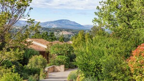 A pathway leading to a building with a stone wall and a view of a mountainous landscape. - Terre Blanche Hotel Spa Golf Resort (Tourrettes)