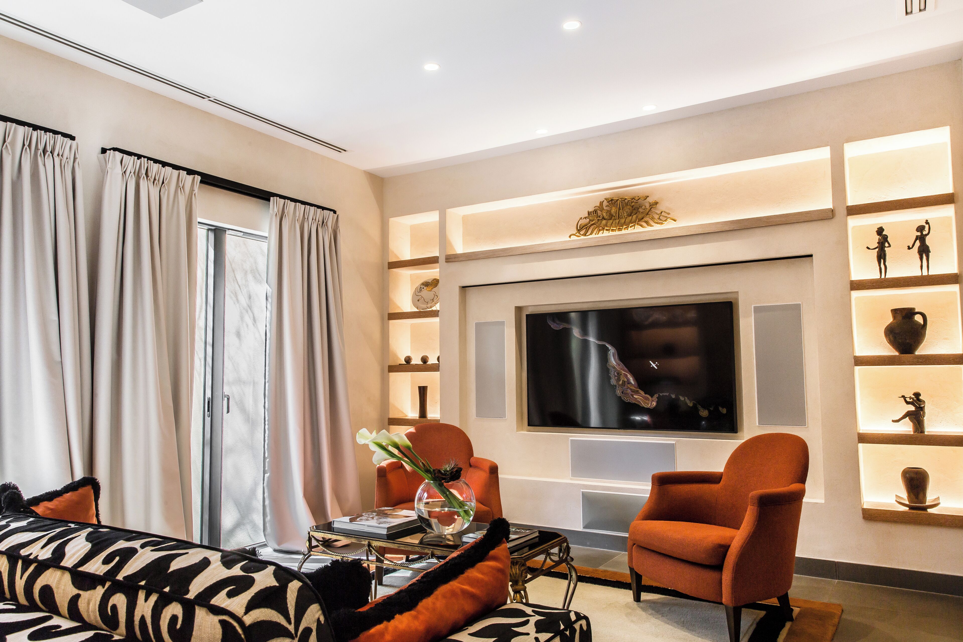 Een moderne woonkamer met een bank, fauteuils, een salontafel en een televisie.