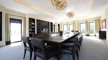 A spacious conference room with a long table, multiple chairs, and a large chandelier.